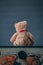 Teddy bear sits on a chest while facing a grey seamless background