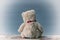 Teddy bear sits on a chest while facing a grey seamless background