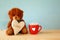 teddy bear sitting and holding a heart next to cup of coffee