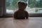 Teddy bear toy sitting by a large window looking out