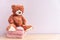 Teddy bear toy and Stack of knitted women`s clothing, warm sweaters, a jacket, a blouse in pastel pink colors