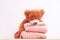 Teddy bear toy and Stack of knitted women`s clothing, warm sweaters, a jacket, a blouse in pastel pink colors