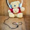 Teddy bear with white headphone and heart shaped cables on wood