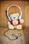 Teddy bear with white headphone and heart shaped cables on wood