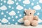 Teddy bear on white wooden table near wall with painted sky, space for text. Baby room interior