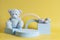Teddy bear, wooden building stone educational toys and geometric shapes podium platform on yellow background. Front view