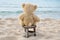 Teddy bear on wooden stool in sand