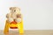 Teddy bear with yellow potty on table against light background, space for text. Toilet training