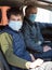 Teen age child with his father wearing medical mask inside the car, young boy and senior man