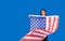 Teen Asian women holding the US flag with a smile of joy on a blue background..Asian-American women are proud of the American flag