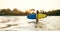 Teen boy with blue and yellow surfboard entering the waves for surfing with sunset rays on palm trees grove. Happy childhood and