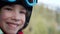 Teen boy in a helmet and goggles sits in a ski lift cabin. The child laughs happily. Fun holidays in the mountains