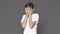 Teen boy hiding face in hands, grey background