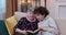 Teen Boy and his grandmother reading book at home. Senior granny reading book together with grandson sitting on sofa