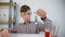 Teen boy is mixing blue color pill in tube doing chemistry experiments.