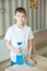 Teen boy puts detergent on the table. In his hand he holds a blue cloth to wipe off the dirt. The concept of cleaning, order,