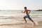 Teen boy is running along the beach