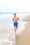 Teen boy runs along the beach