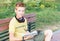 Teen boy is sitting with books on the bench.