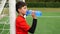 Teen boy soccer player drinks water from a plastic bottle