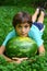 Teen boy with whole water melon lay on green grass