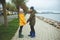 Teen brother and sister walking on Baltic coastline in high rubber boots and colorful jackets