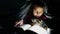 Teen child reading girl reads a book dog at night with flashlight lying under a blanket