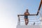 Teen on deck of ferry boat leaning on safety rail and looking down.