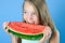 Teen girl bites a ripe juicy watermelon.