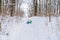 A teen girl in a blue coat tries to move on a sledge from a snow slide and falls