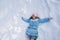 A teen girl in a blue coat tries to move on a sledge from a snow slide and falls