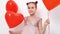 teen girl dances, laughs with red balls of hearts near white wall