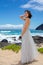 Teen girl in dress by lava shore of Hawaiian ocean