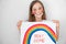 Teen girl drew rainbow and poster stay home.
