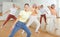 Teen girl with family exercising dance moves with group of people in dance center