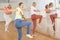 Teen girl with family exercising dance moves with group of people in dance center