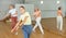 Teen girl with family exercising dance moves with group of people in dance center