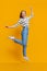 Teen girl having fun, jumping on orange studio background