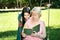 Teen girl and her grandmother read a book in the park horizontal