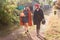 Teen girl with her mom go on rural track with pumpkin and sunflower in the hands