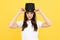 Teen girl in illusionist hat. Woman in magician top hat, black vintage cylinder cap on yellow background. Girl circus