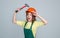 teen girl laborer in protective helmet and uniform on grey background use hammer, protection