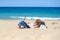 A teen girl lies on the beach with a laptop