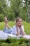 Teen girl lies listens to music in headphones on the grass in the park with books and notebooks