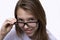 Teen girl with long hair in glasses and white shirt. Camera view, portrait close-up