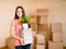 Teen girl moving house to college, holding pile books and plant