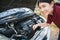 Teen girl open car hood check engine oil level enjoy and smile