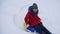 Teen girl plays in a winter park on christmas holidays. girl slides in winter in snow from high hill on sled and an