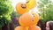 Teen girl posing with bunch of orange halloween balloons sitting on the street.