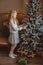 Teen girl with present near Christmas tree standing